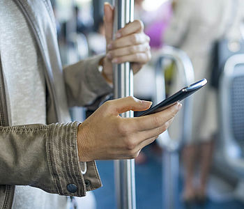 Eine Frau fährt Bus und schaut dabei auf ihr Smartphone