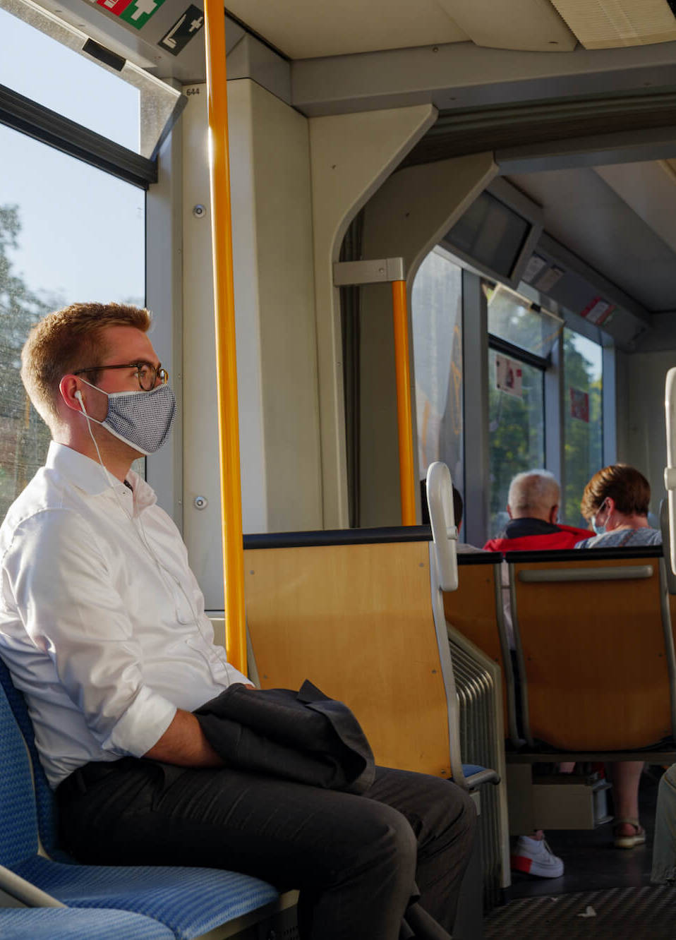 Ein Mann trägt Maske und fährt Bahn.