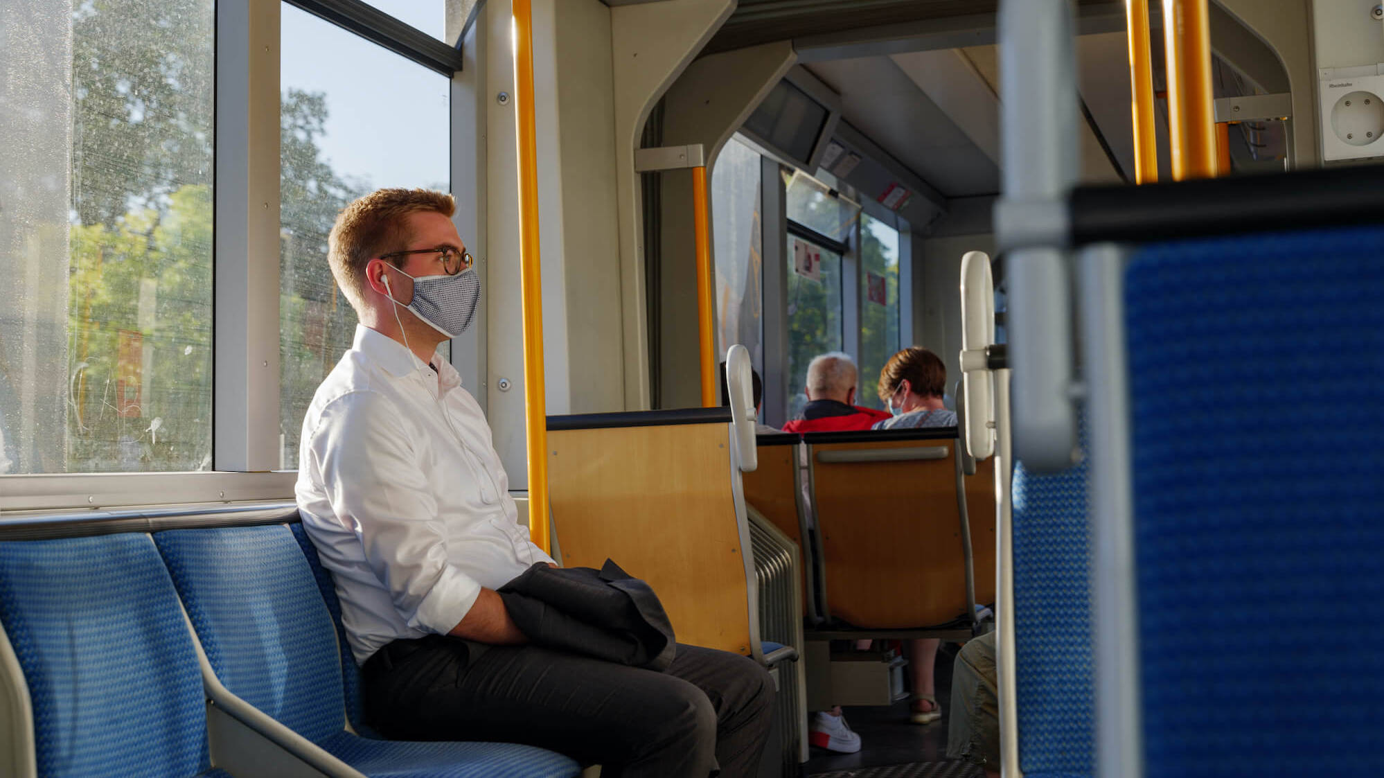 Ein Mann trägt Maske und fährt Bahn.